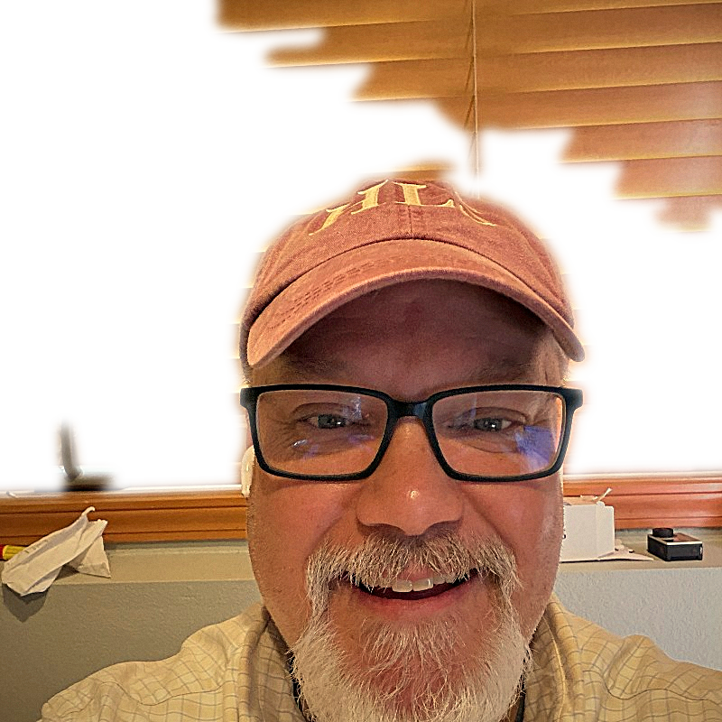 Tom smiling in a red cap indoors